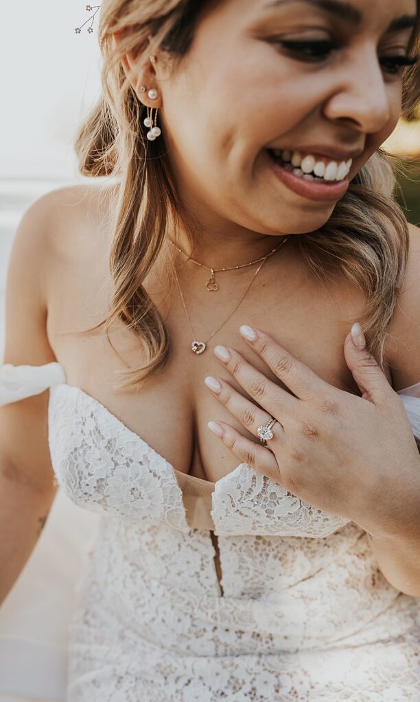 bridal details of ring and necklace with bride smiling 