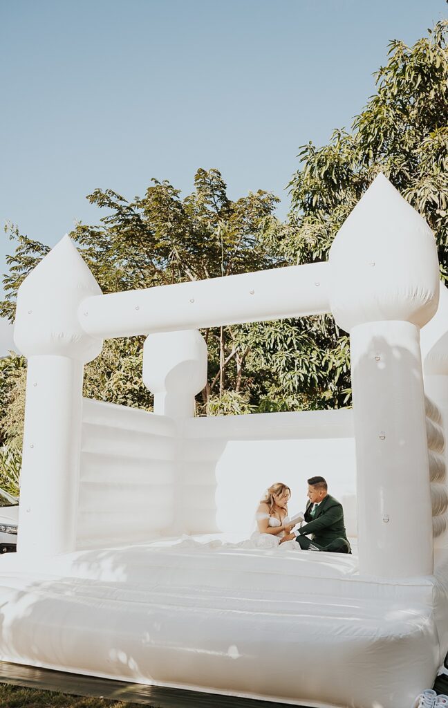 bride and groom in white bouncy house reading wedding vows 