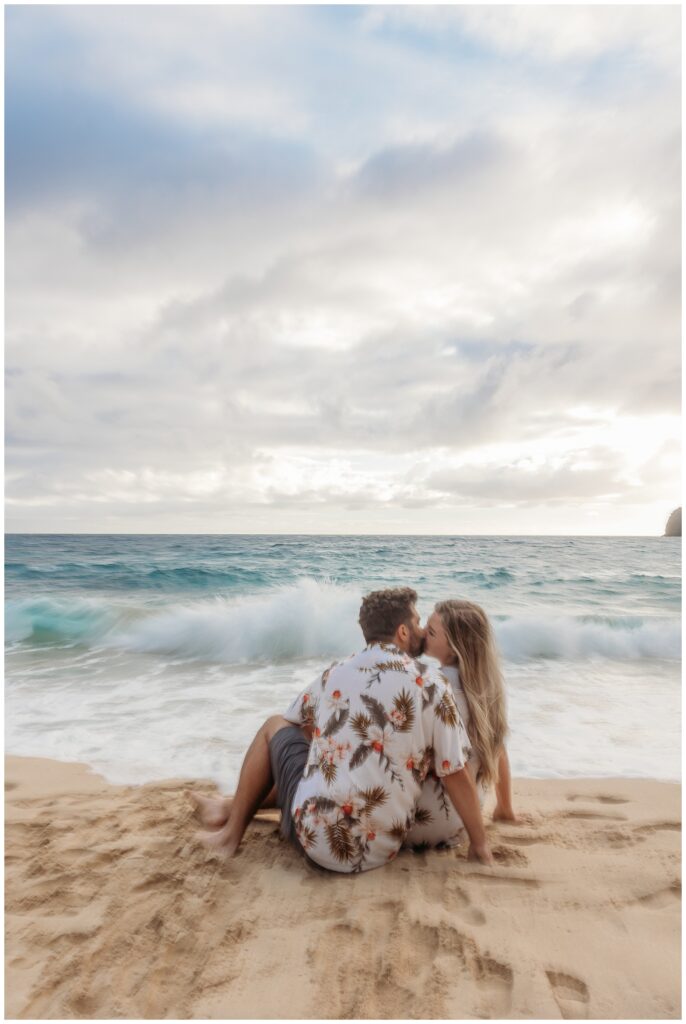 couple kissing on a beach with waves crashing